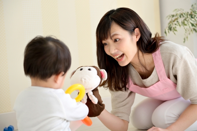 乳幼児を笑顔であやす1人の女性
