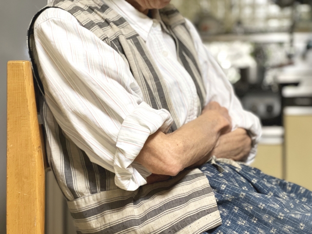 腕組みをして動こうとしない椅子に座った高齢女性