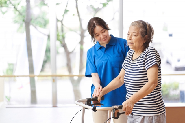 歩行訓練をする高齢女性に付き添う若い女性スタッフ