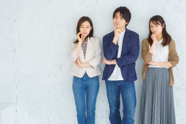 腕組みをして考え込む若い男女3人