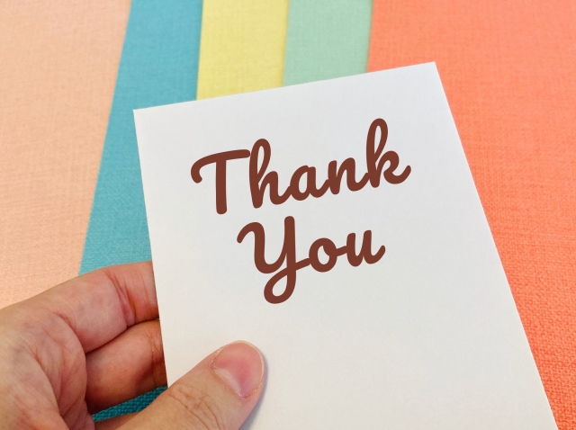 Thank youと書かれた手のひらサイズのカードを持つ人の手