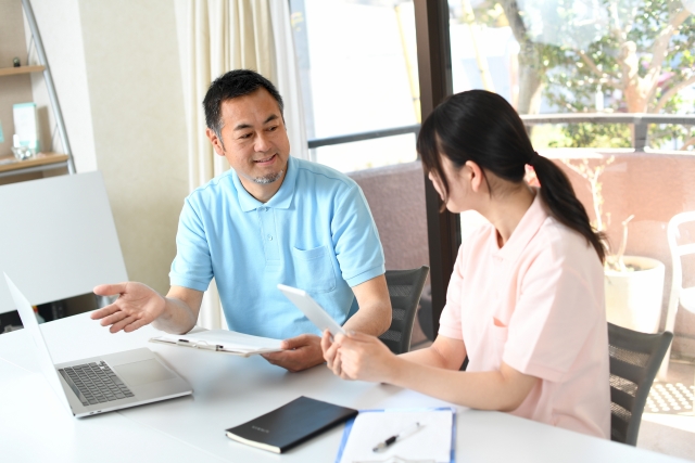 パソコンと資料を見ながら打合せをする介護スタッフ男女