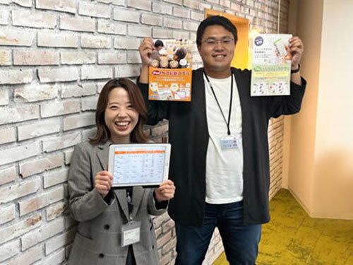 写真:今回ブースで紹介する「ケア記録アプリ」と「持ち物チェックアプリ」のチラシを掲げる担当スタッフ